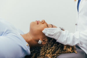 A Dermatology Aesthetics of Northern Kentucky provider wearing while gloves carefully applies one of our many chemical peels near Cincinnati to a female patient's skin.