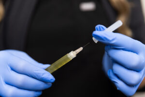 A female Dermatology Aesthetics of Northern Kentucky inspects a needle of platelet-rich fibrin before administering PRF injections near Cincinnati.